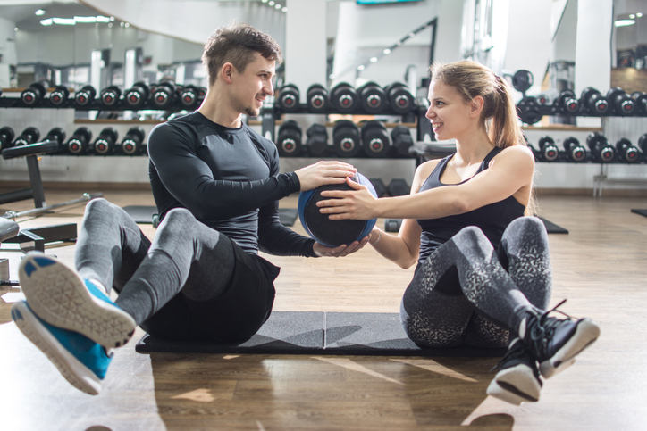 Sporty fitness couple doing abdominal exercises with medicine ball in the gym.